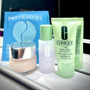 Flatlay of skincare products used before makeup, including scrub, toner, under-eye patch and moisturizer