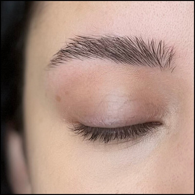 Eyebrows after shaping with tweezers and trimming, looking more defined but still natural, with no makeup applied yet
