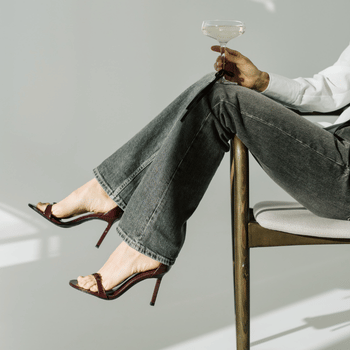 Woman in heels sitting on a chair holding glass